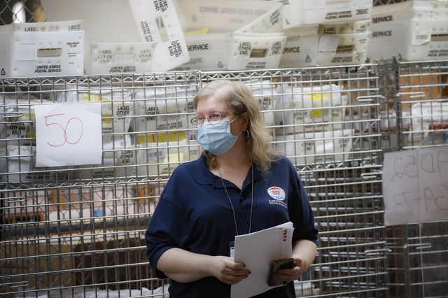 A NYC Votes workers stands in front of cages containing absentee ballots in NYC.